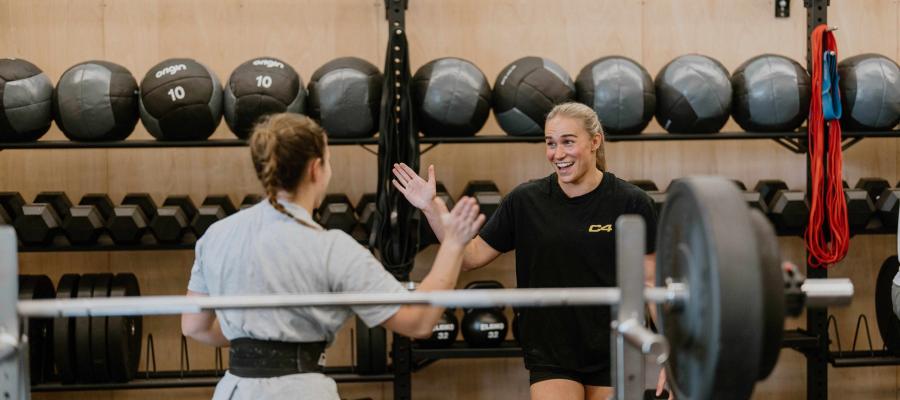 Image of two girls high fiving in crossfit gym