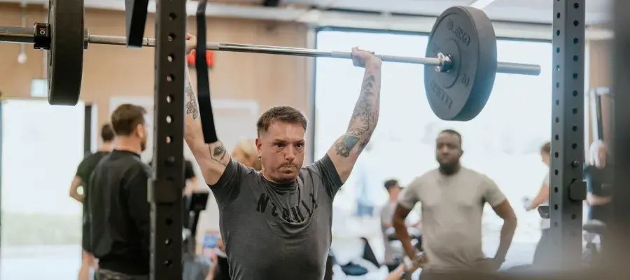 Image of man holding weights over head in crossfit gym