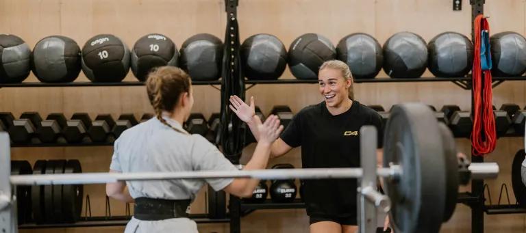 Image of two girls high fiving in crossfit gym
