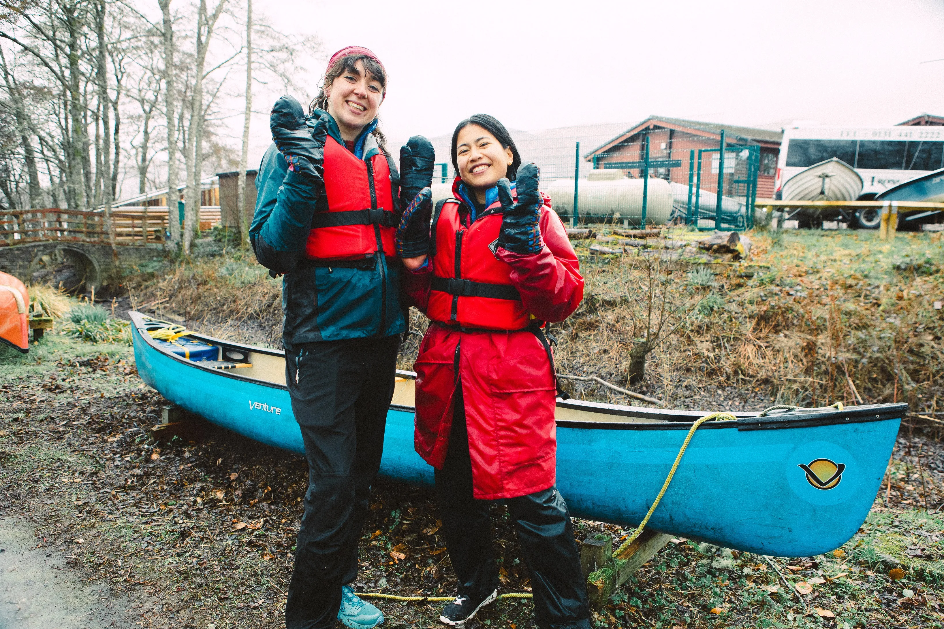 Two happy people in front of a canoe on the banks of the Loch