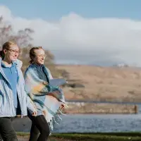 2 people walking next to a Loch in warm clothing