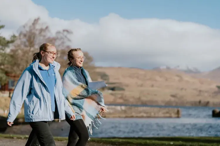 2 people walking next to a Loch in warm clothing